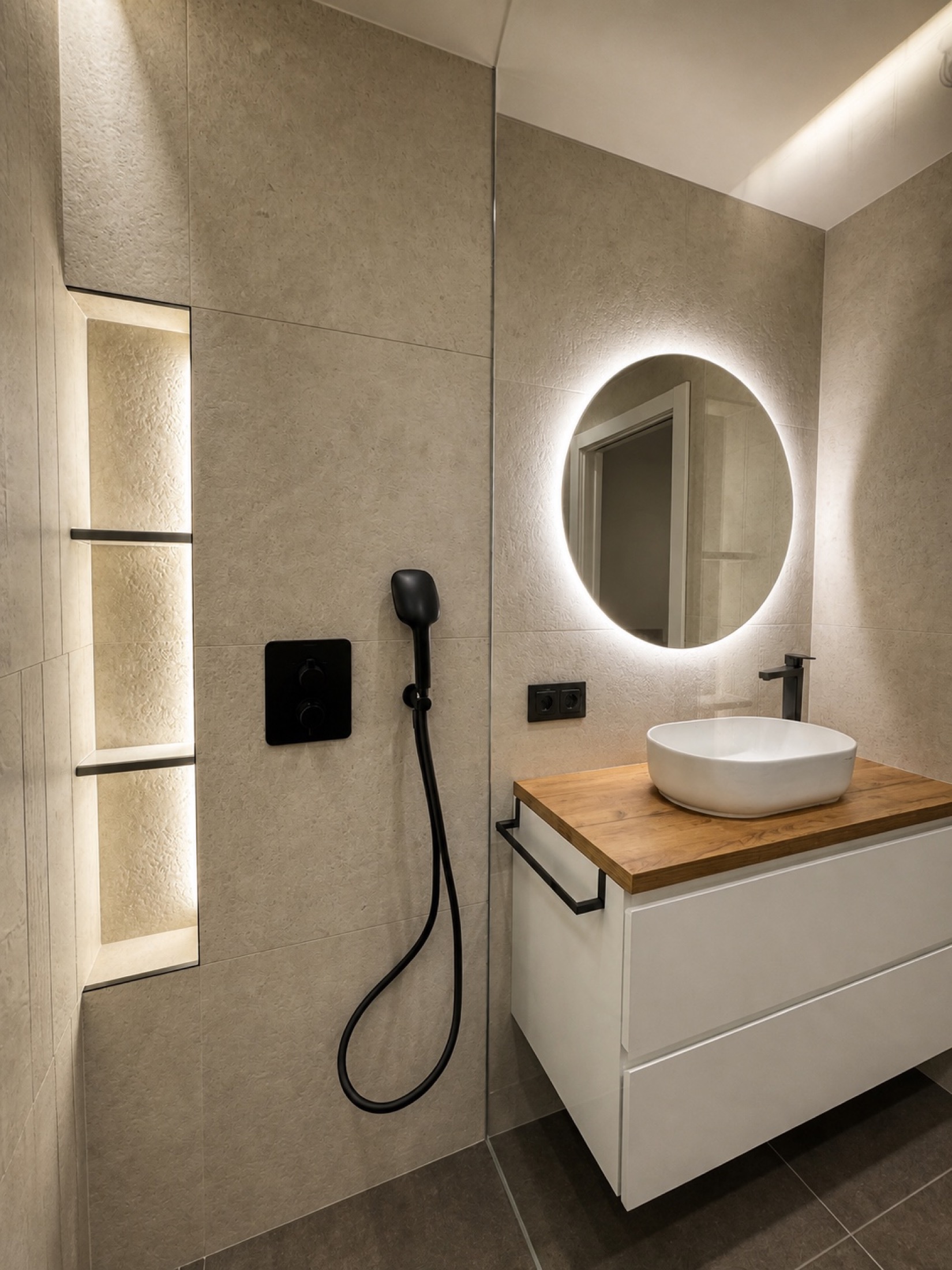 Luz en vertical. Las hornacinas iluminadas aprovechan la pared de la ducha para guardar productos. El lavabo sobre encimera combina madera, blanco y grifería negra.